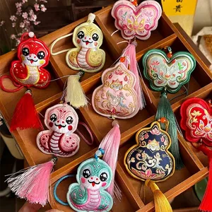 Handmade embroidered snake and butterfly sachet pendants with colorful tassels in wooden box