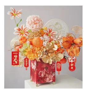 Lebhaftes Neujahrsblumengesteck mit roten Pfingstrosen und goldenen Blättern in Geschenkbox