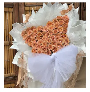 Detalle de ramo de rosas naranjas en forma de corazón con gran lazo de tul blanco.