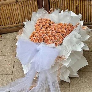 Ramo de rosas café en forma de corazón con gran lazo de encaje blanco y decoraciones