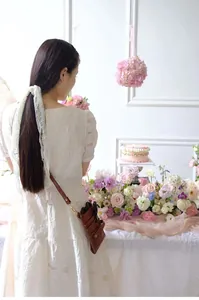Floral artist wearing a brown leather tool pouch in a professional florist setting.