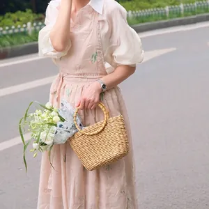 Elegant pink floral embroidered apron with woven straw flower basket in outdoor setting