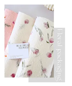 Primer plano de papel floral artesanal con texturas naturales y flores secas incrustadas.