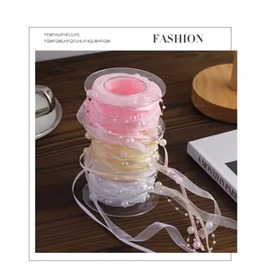 Detailed view of pink and cream organza ribbons with elegant pearl beads on clear spools.