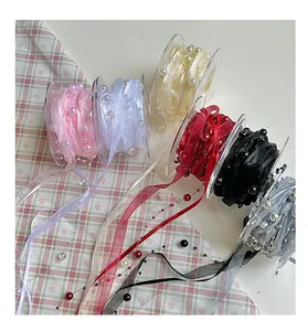 Close-up of pearl-embellished satin ribbons in various colors for gift wrapping and floral decor.