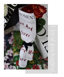Close-up view of white floral wrapping paper with artistic red handwritten text details