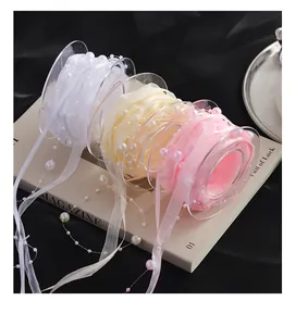 Close-up of pearl-embellished ribbons in white, cream, and pink for gift wrapping.
