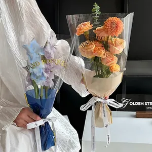 Elegant transparent floral bouquet packaging bags with decorative gold text and ribbons