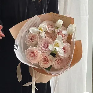 Hand-held rose bouquet wrapped in honeycomb textured paper with waterproof inner lining