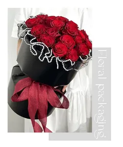 Elegante envoltorio floral negro con ribete de perlas y gran lazo rojo.