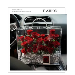Close-up of a clear acrylic handheld flower gift box with red roses inside a car interior