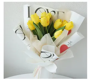 Detail view of yellow tulip bouquet in elegant LOVE pattern floral wrapping paper.