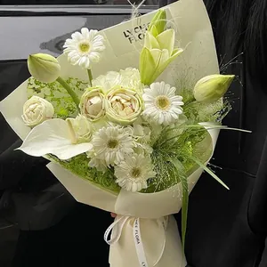 Eleganter handgefertigter weißer Blumenstrauß mit Lilien und Gerbera in Netzverpackung