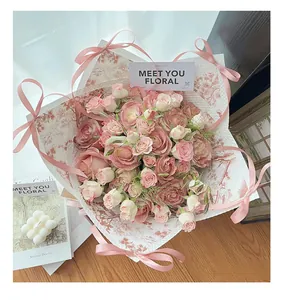 Gros plan de roses enveloppées dans du papier à imprimé floral rétro européen avec ruban rose.