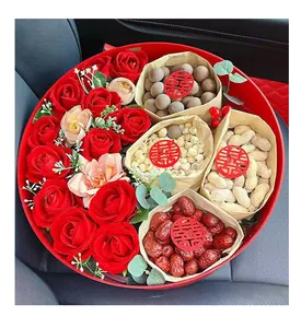 Detail view of round red wedding gift box with roses and bags of traditional snacks