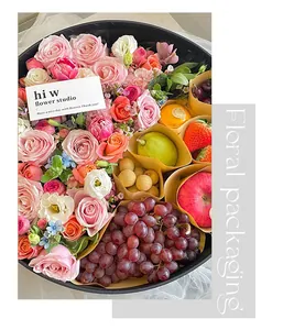 Close-up detail of a circular floral packaging box filled with fresh flowers and fruits.