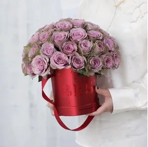 Elegant red cylindrical flower gift hug bucket with purple roses being held by a model