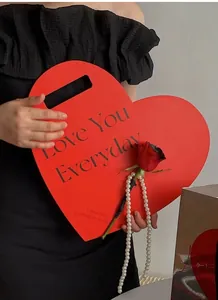 Detail view of a large red heart-shaped gift box featuring elegant handle and romantic text