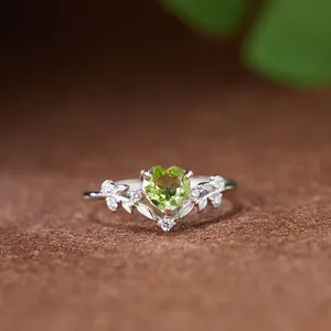 Gros plan détaillé d'une bague en argent à motif feuilles avec péridot en forme de cœur