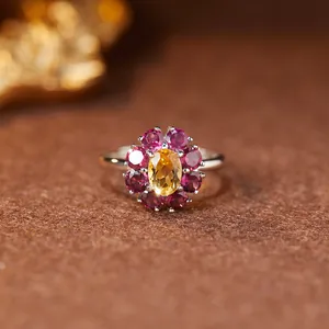 Vista macro di un anello a fiore in citrino e rubino in argento sterling con dettagli.