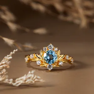 Gros plan sur une bague vintage branche dorée ornée d'une topaze bleue centrale éclatante