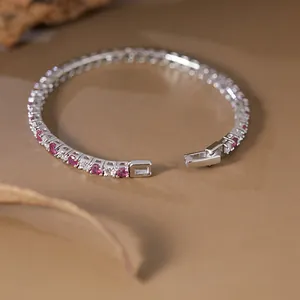 Detailed close-up view of S925 silver tennis bracelet with ruby and clear gemstones on warm background