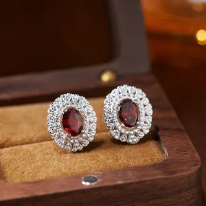 Detailed macro shot of S925 silver earrings with oval red garnets and halo crystal setting