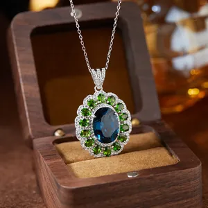 Macro detail of S925 silver pendant with oval blue topaz and green gemstone halo setting