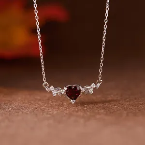 Gros plan d'un pendentif cœur en grenat avec accents de feuilles en argent sterling S925
