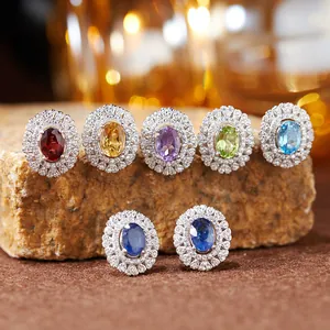 Macro view of multiple colored gemstone halo stud earrings on a natural stone surface