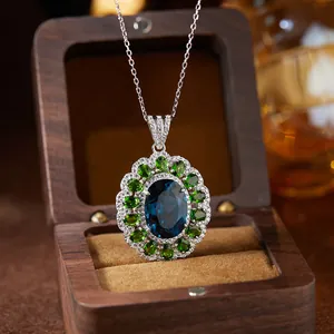Detailed macro shot of S925 silver pendant with blue topaz and green emeralds in wood box