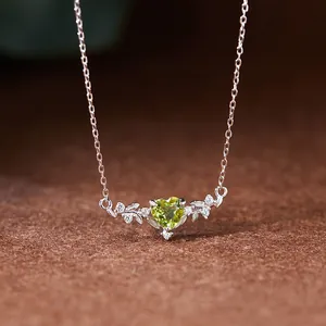 Détail d'un collier en péridot en forme de cœur avec un design de feuille d'argent