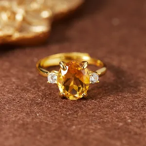 Gros plan détaillé montrant la citrine ovale et le serti à quatre griffes de la bague dorée