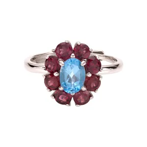 Dettaglio di un anello floreale in argento s925 con topazio blu e pietre preziose rosse