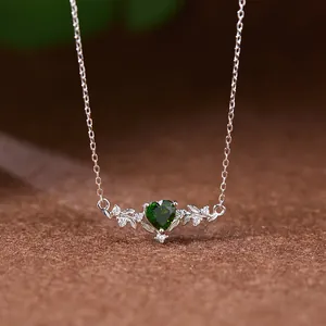 Détail d'un élégant collier en argent avec pierre verte en forme de cœur et motif feuilles