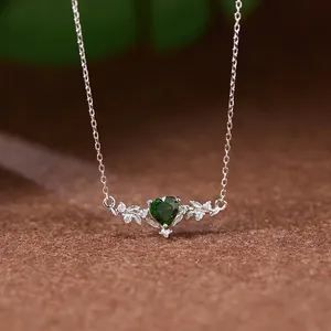 Gros plan d'un collier en argent sterling avec une pierre précieuse verte en cœur.