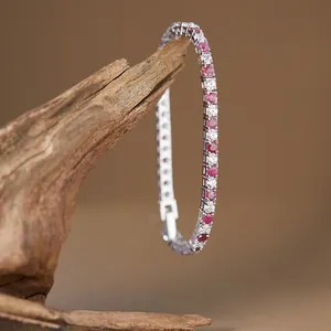 Detailed close-up of a sterling silver tennis bracelet featuring rubies and clear stones.