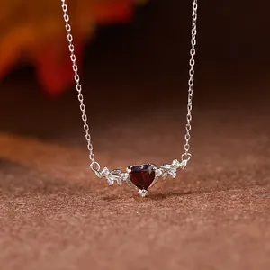Détail d'un collier en grenat en forme de cœur avec des accents de feuilles d'argent