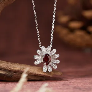 Detailansicht einer silbernen Gänseblümchen-Halskette mit rotem Granat-Edelstein.