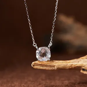 Macro detail of cushion-cut white crystal pendant on S925 silver chain over natural wood