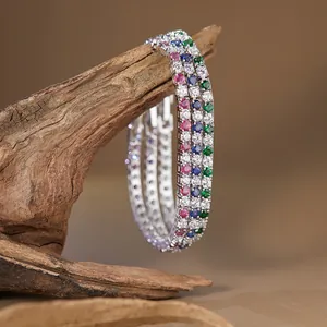 Close-up of three S925 silver tennis bracelets with vibrant multicolored gemstones on wood.
