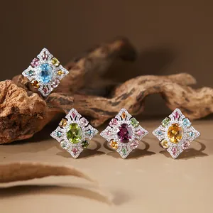 Detailed view of vintage S925 silver rings set with colorful natural gemstones on wood.