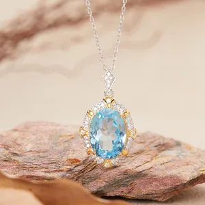 Close-up of elegant oval blue topaz pendant on silver chain atop natural rock.
