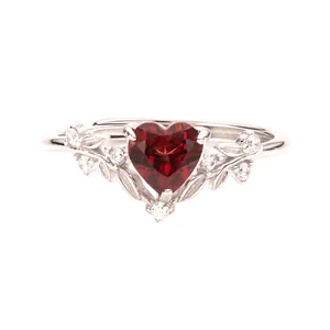 Gros plan d'une bague en argent s925 avec grenat rouge en cœur et motifs feuilles