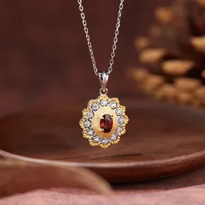 Detailed close-up of a vintage sunburst pendant necklace with red garnet and silver chain.