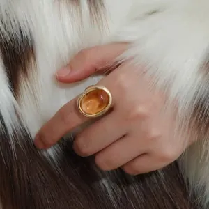 Detail shot of a luxury bathtub ring with a large oval honey citrine on a model's hand.