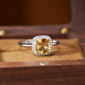 Macro detail of a cushion-cut yellow citrine halo ring resting in a rustic wooden jewelry box