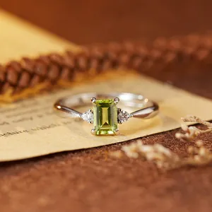 Close-up of a S925 silver ring with a rectangular emerald-cut green gemstone and side diamonds