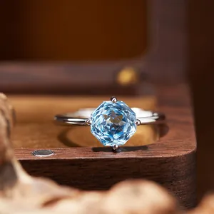 Detail view of an octagonal cut blue topaz silver ring in a wooden jewelry box