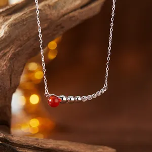 Nahaufnahme einer S925 Silberhalskette mit roter Achatperle und funkelnden Steinen